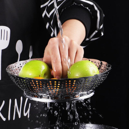 Person washing green apples under running water in a colander with a black background.