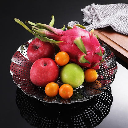 Fruit including dragon fruit, apples, and oranges on a perforated metal tray.