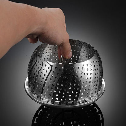 Metal steamer basket held by a hand against a dark background